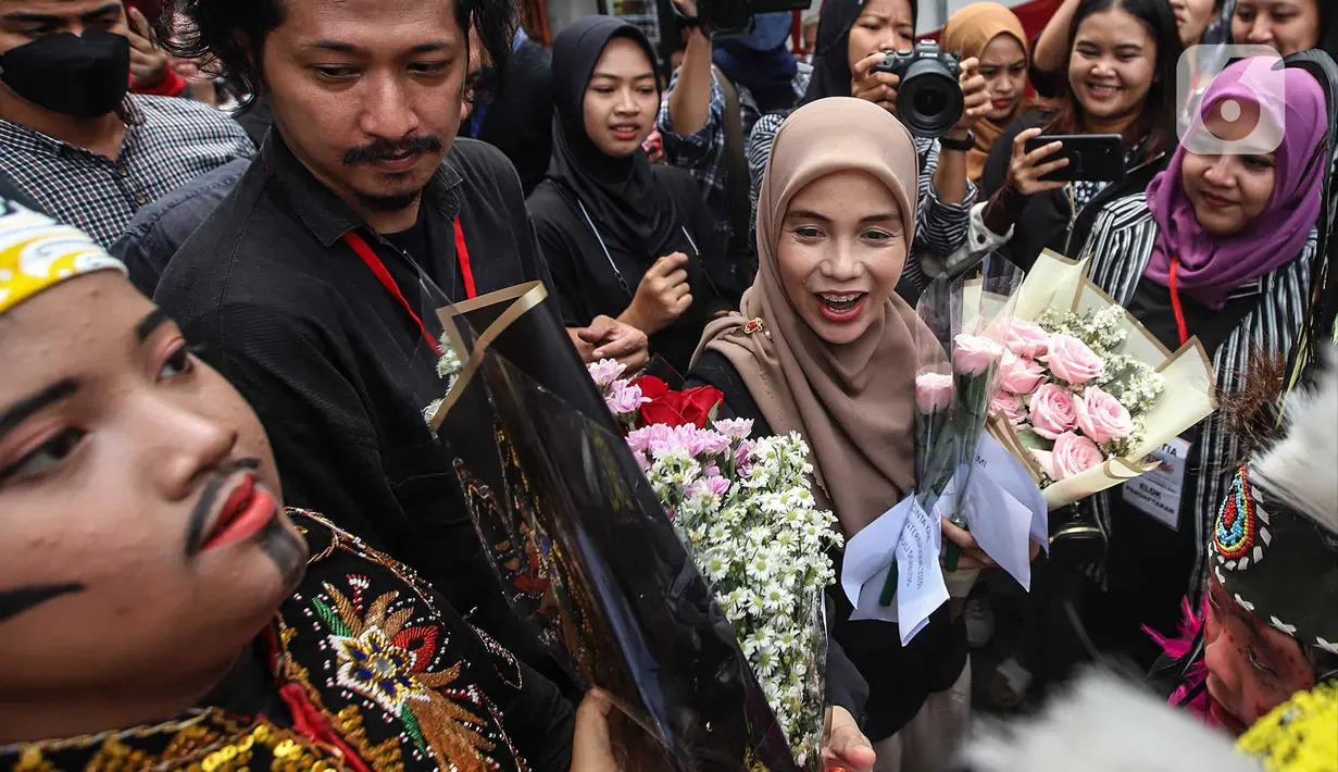 Siti Atiqoh Supriyanti menghadiri acara Hari Disabilitas Internasional yang diselenggarakan oleh Komunitas Disabilitas Tunarungu Indonesia di Bumi Pospera, Cipinang, Jakarta, Minggu (3/12/2023). Atiqoh tampak bahagia disambut oleh para penyandang disabilitas dengan rangkaian bunga. (Liputan6.com/Herman Zakharia)