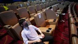 Pengunjung memakai masker duduk menjauh untuk mencegah penyebaran Covid-19 ketika mereka menonton film di bioskop Paragon Cineplex di Bangkok, Thailand, Senin (1/6/2020). (AP Photo/Sakchai Lalit)