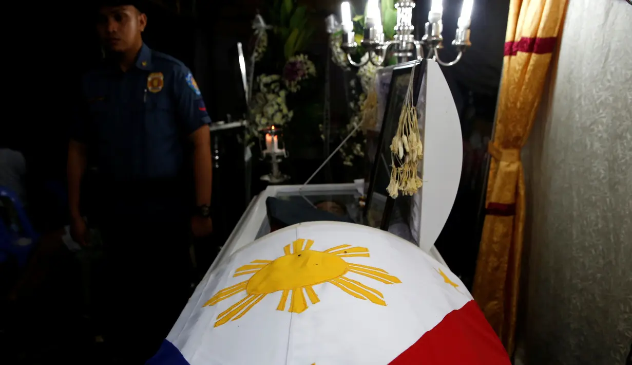 Jasad petugas polisi, Rancel Cruz terbaring di atas peti mati usai ditembak pecandu narkoba di Manila, Filipina, (19/10). Filipina terus membasmi peredaran narkoba dengan cara menembak di tempat bagi pecandu dan pengedar narkoba. (REUTERS/Erik De Castro)