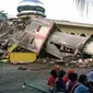 Sejumlah warga berkumpul di luar sebuah masjid yang mengalami kerusakan akibat gempa yang mengguncang  Kabupaten Pidie Jaya, Aceh, Rabu (7/12). Seperti dirilis BMKG, gempa berkekuatan 6,4 SR mengguncang Aceh sekitar pukul 05.03 WIB. (Zian Muttaqien/AFP)