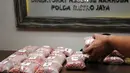Salah satu petugas merapikan barang bukti narkotika jenis ekstasi saat jumpa pers di Dit Resnarkoba Polda Metro Jaya, Kamis (13/11/2014). 37.214 butir ekstasy berhasil diamankan Dit Resnarkoba Polda Metro Jaya. (Liputan6.com/Helmi Fithriansyah)