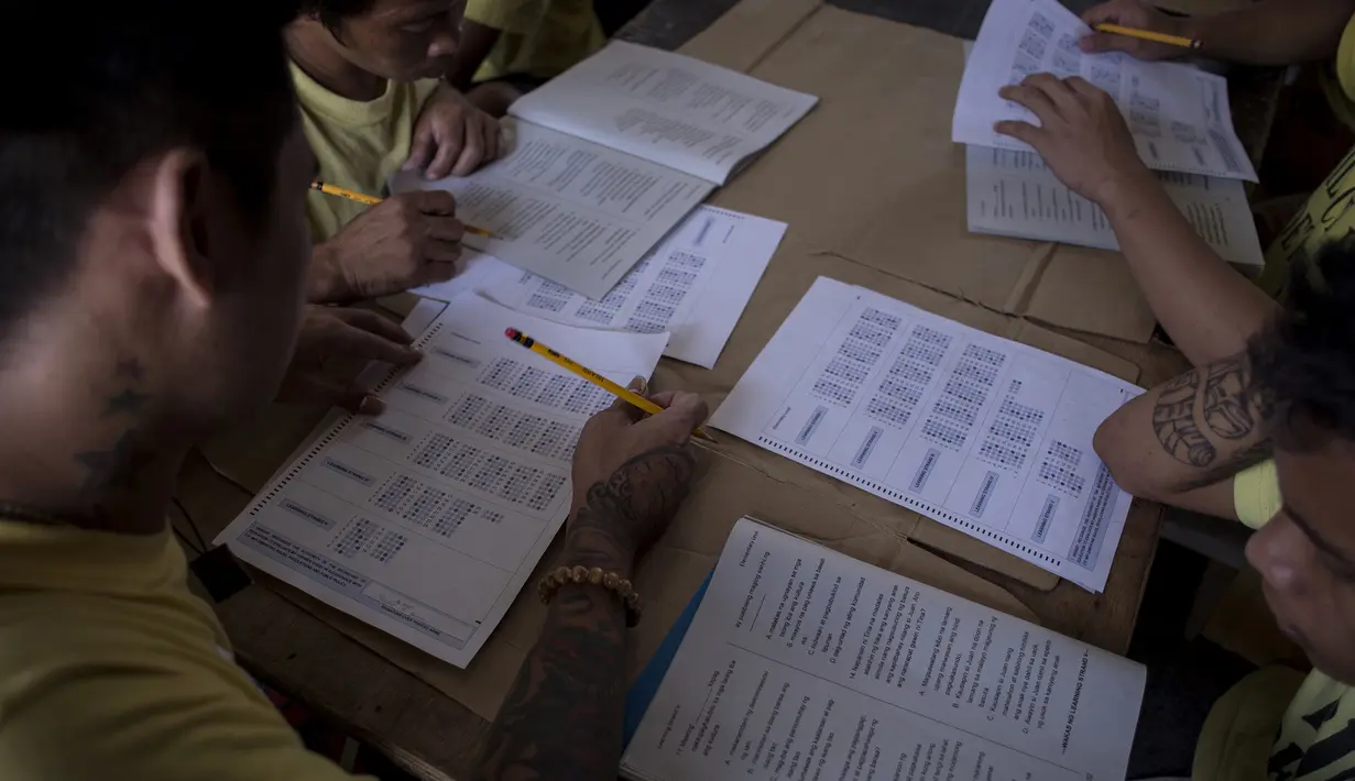 Narapidana mengerjakan soal Ujian Akreditasi Nasional dan Pemeriksaan Kesetaraan di Penjara Manila City, Filipina, Minggu (19/11). Sekitar 900 narapidana mengikuti ujian untuk menjadi modal pendidikan mereka jika bebas dari penjara. (NOEL CELIS/AFP)