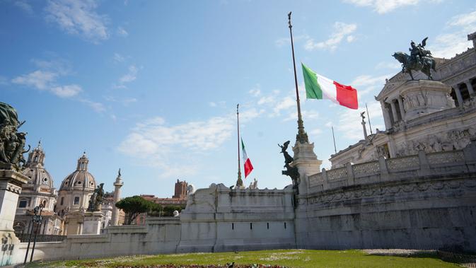 Bendera nasional Italia dikibarkan setengah tiang saat mengheningkan cipta selama satu menit di depan Monumen Prajurit Tak Dikenal, Roma, Selasa (31/3/2020). Italia mengheningkan cipta dan menaikkan bendera setengah tiang menghormati para korban virus corona dan keluarga mereka (AP/Andrew Medichini)