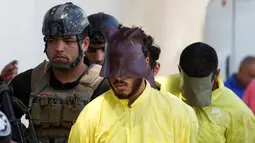 Militer Irak mengawal sejumlah pria yang diduga militan ISIS saat akan konferensi pers di Baghdad, Irak (7/9). Militer Irak menangkap beberapa militan ISIS usai kembali merebut wilayah yang dikuasai. (REUTERS/Khalid al Mousily)