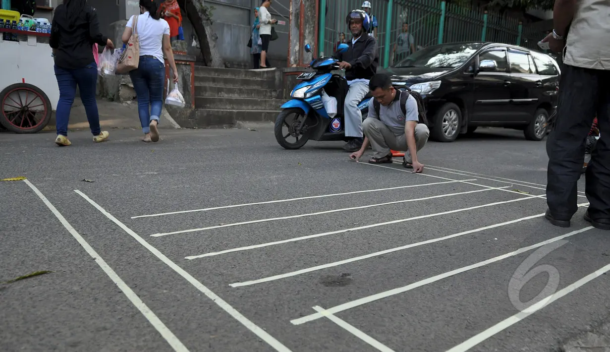 Seorang relawan dari Koalisi Pejalan Kaki membuat pola untuk jalur zebra cross di depan Stasiun Sudirman, Jakarta, Jumat (13/3/2015). (Liputan6.com/Faizal Fanani)