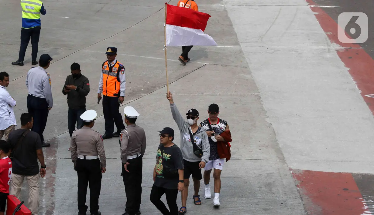 Seorang warga mengibarkan bendera merah putih saat perayaan pawai Timnas U-22 dan Juara SEA Games 2023 di kawasan Bundaran HI, Jakarta, Jumat (19/5/2023). (Liputan6.com/Herman Zakharia)