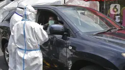 Petugas berpakaian APD lengkap melayani pasien yang secara mandiri melakukan swab test drive thru di halaman parkir rumah sakit di Jakarta, Rabu (12/5/2020). Swab test drive thru dilakukan untuk mendeteksi dan mencegah penyebaran virus corona COVID-19. (Liputan6.com/Johan Tallo)