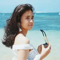 Michelle Ziudith perempuan berusia 25 tahun ini tampil begitu menawan saat berlibur di pantai. Ia memakai pakaian putih dan memegan kacamata. Gaya penampilannya yang simpel tapi menawan ini tuai pujian. (Liputan6.com/IG/@michelleziu)