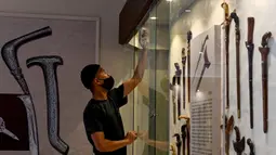 Seorang pekerja membersihkan etalase yang memajang keris jelang pameran persenjataan tradisional di Museum Aceh, Banda Aceh, Aceh, Jumat (15/10/2021). Pameran Senjata 2021 menampilkan 176 jenis senjata yang merupakan koleksi Museum Aceh. (CHAIDEER MAHYUDDIN/AFP)