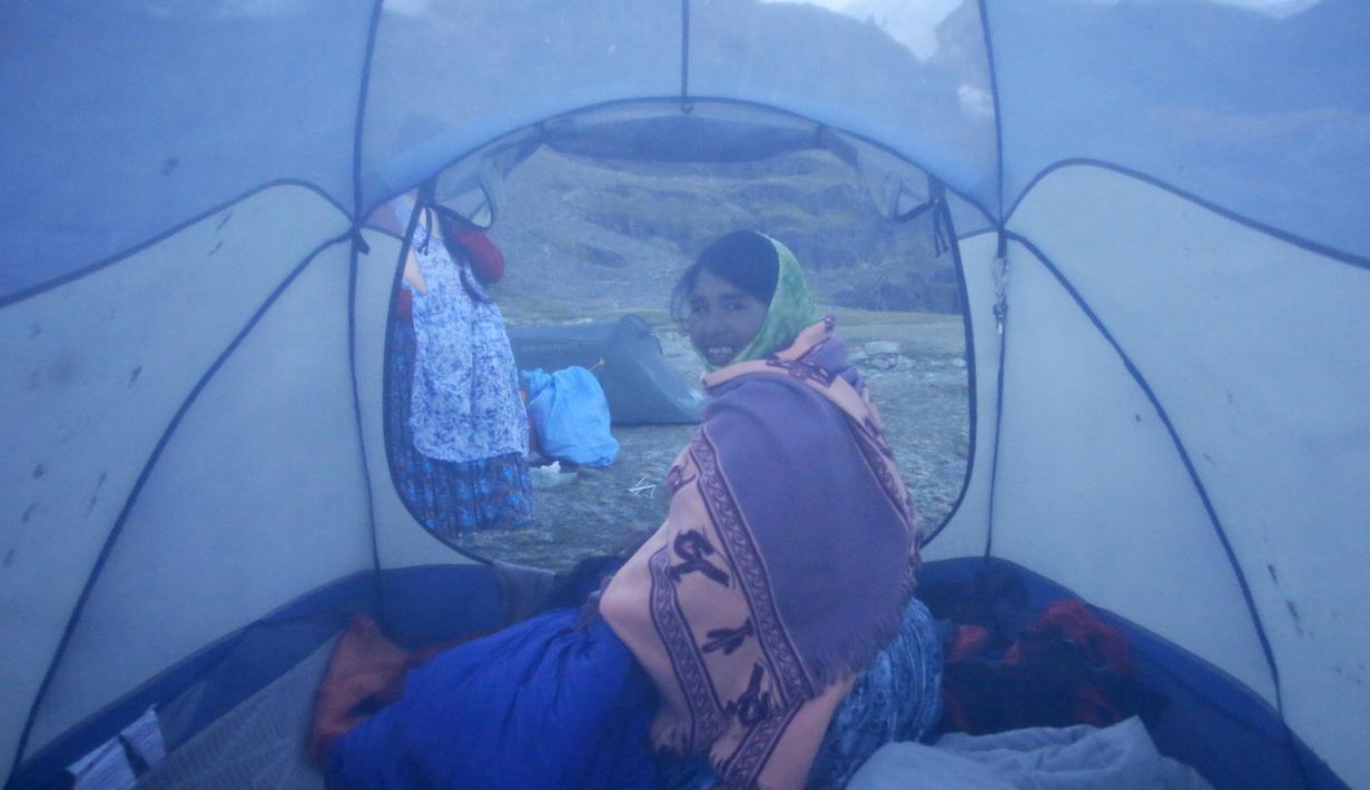 Perempuan suku Aymara duduk di tendanya sebelum naik gunung Illimani, di Paz, Bolivia, (16/4). Perempuan suku Aymara yang berprofesi sebagai tukang masak dan angkut barang atau porter ini selalu mengenakan pakaian tradisional. (REUTERS/David Mercado)
