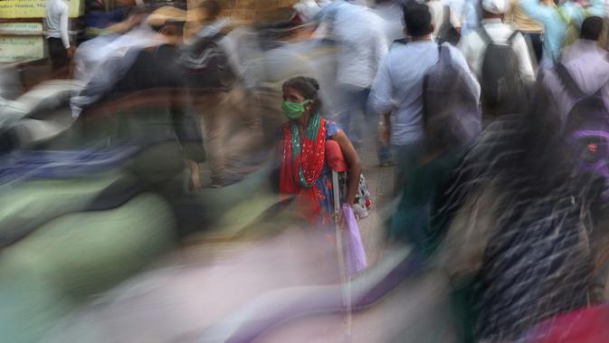 Seorang perempuan meminta sedekah saat orang-orang bergegas menaiki kereta di luar terminal kereta Chhatrapati Shivaji Maharaj di Mumbai, India, 9 November 2020. Penghitungan kasus virus corona terkonfirmasi di India, terbesar kedua di dunia, lebih dari 8,5 juta. (AP Photo/Rafiq Maqbool)