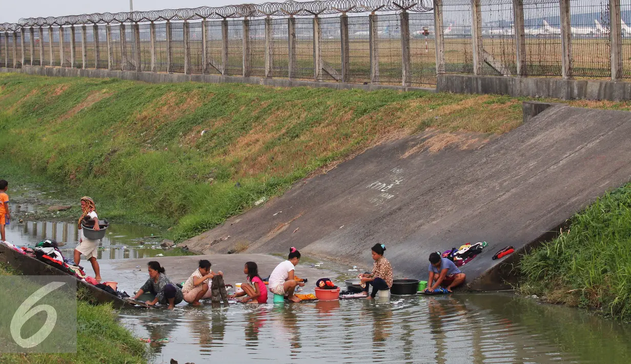 Warga mencuci pakaian di sungai yang menjadi pembatas di area Bandara Soetta, Tangerang (28/9/2015). Akibat kemarau panjang membuat pasokan air menjadi kering sehinga warga yang bermukim nekat menerobos pagar untuk mencuci. (Liputan6.com/Angga Yuniar)