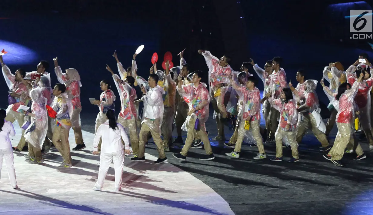 Parade sukarelawan saat upacara Penutupan Asian Games 2018 di Stadion Utama Gelora Bung Karno, Jakarta, Minggu (2/9). Mereka mengenakan jas hujan yang mengguyur Jakarta. (Liputan6.com/Helmi Fithriansyah)