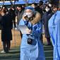 Seorang petugas kesehatan (tengah) yang mengenakan alat pelindung diri tiba di pusat pengujian virus corona COVID-19, Seoul, Korea Selatan, Rabu (16/2/2022). Kasus COVID-19 harian Korea Selatan meningkat tajam mencapai angka tertinggi baru yaitu lebih dari 90 ribu. (Jung Yeon-je/AFP)