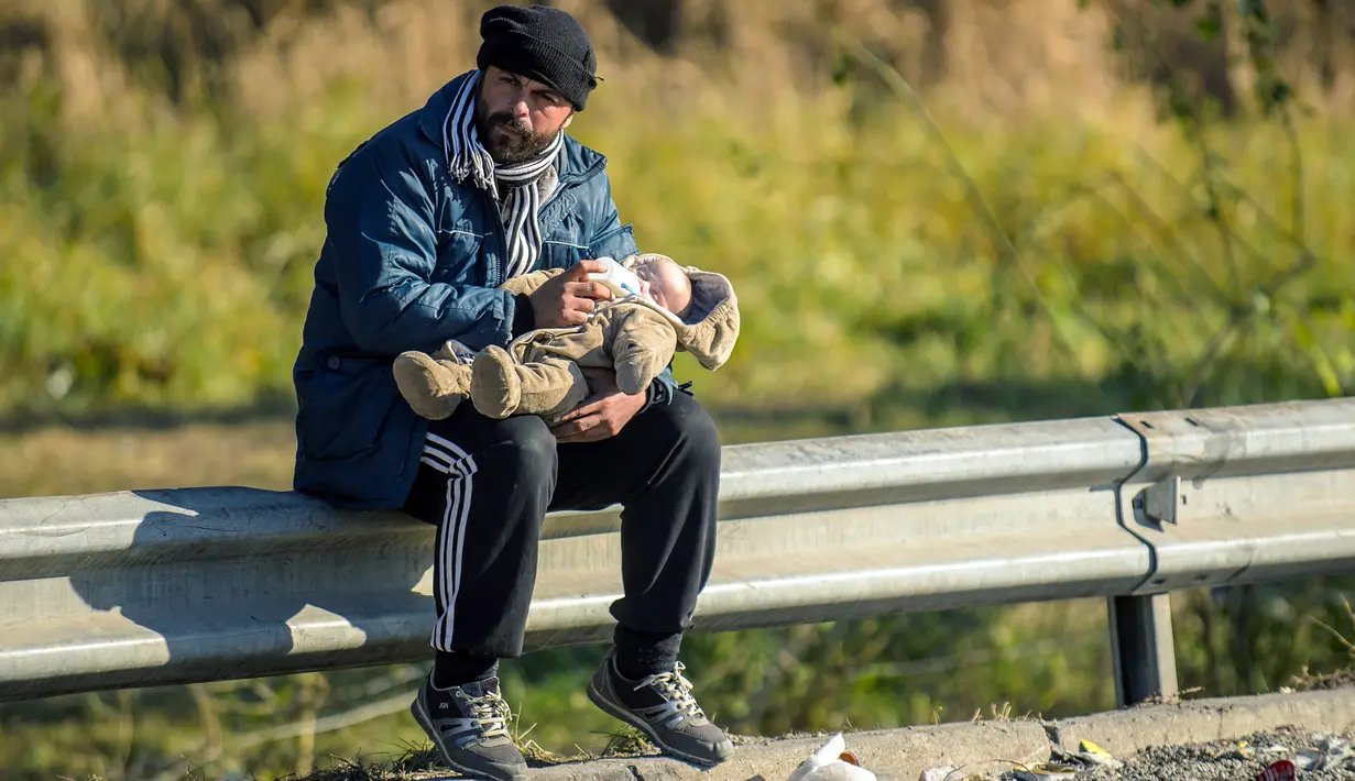 Imigran dan bayinya menunggu untuk menyeberang perbatasan Slovenia - Austria dari kota Sentilj, Selasa (3/11). Slovenia mengatakan kewalahan menghadapi arus ribuan migran yang melintasi wilayah negara itu untuk menuju Eropa barat. (AFP PHOTO/RENE GOMOLJ)