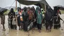 Pengungsi Muslim Rohingya menunggu antrean distribusi makanan di bawah tenda saat hujan di kamp pengungsi Nayapara, Bangladesh (6/10). Bangladesh akan membangun kamp pengungsi terbesar di dunia untuk menampung 800.000 orang. (AFP PHOTO/Fred Dufour)