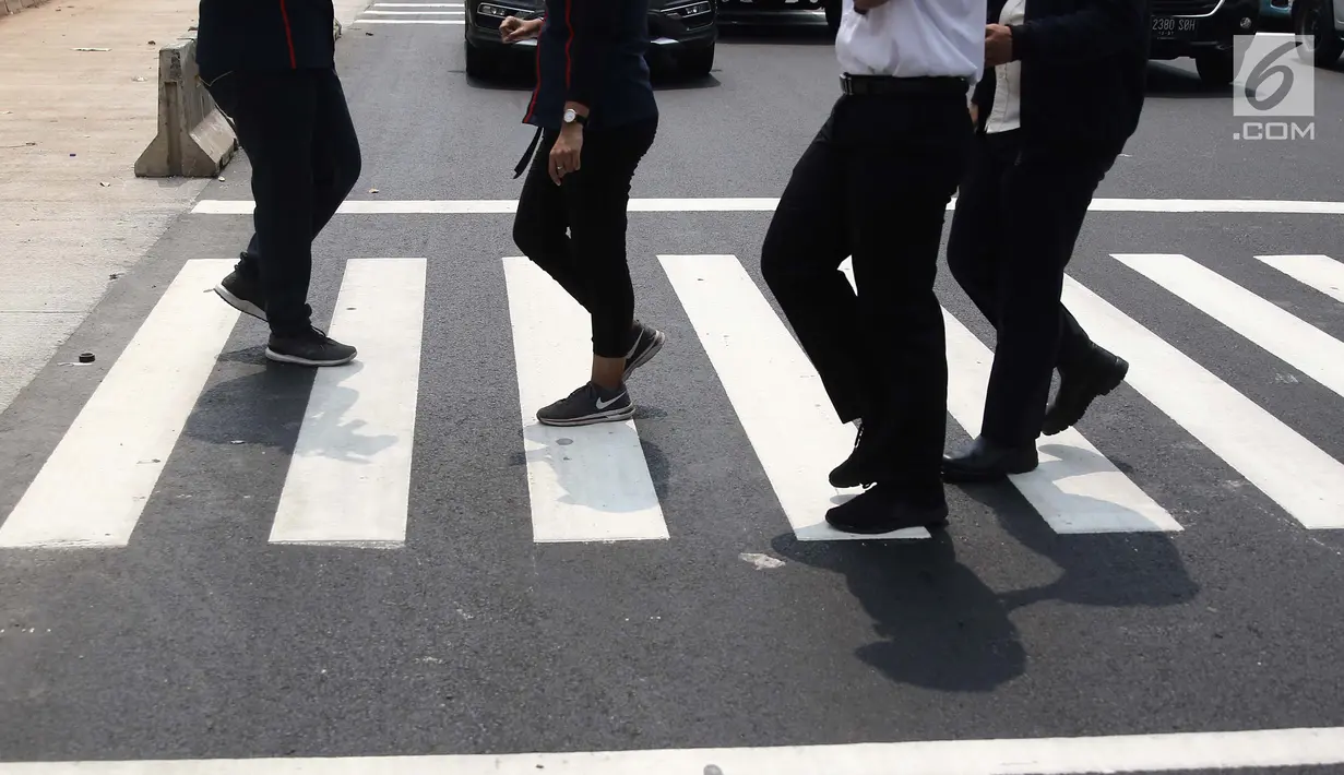 Pejalan kaki sedang menyebrang di pelican crossing di kawasan Thamrin, Jakarta, Minggu (29/7). Pelican crossing di kawasan Thamrin sudah bisa di gunakan pengganti JPO yang akan dibongkar. (Liputan6.com/Herman Zakharia)