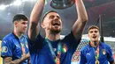 <p>Gelandang Italia Jorginho berpose dengan trofi Kejuaraan Eropa setelah Italia memenangkan pertandingan final UEFA EURO 2020 melawan Inggris di Stadion Wembley di London pada 11 Juli 2021. Kehadiran Jorginho akan memperkuat lini tengah Arsenal yang saat ini sedang dalam perburuan gelar juara Liga Inggris. (Andy Rain / POOL / AFP)</p>