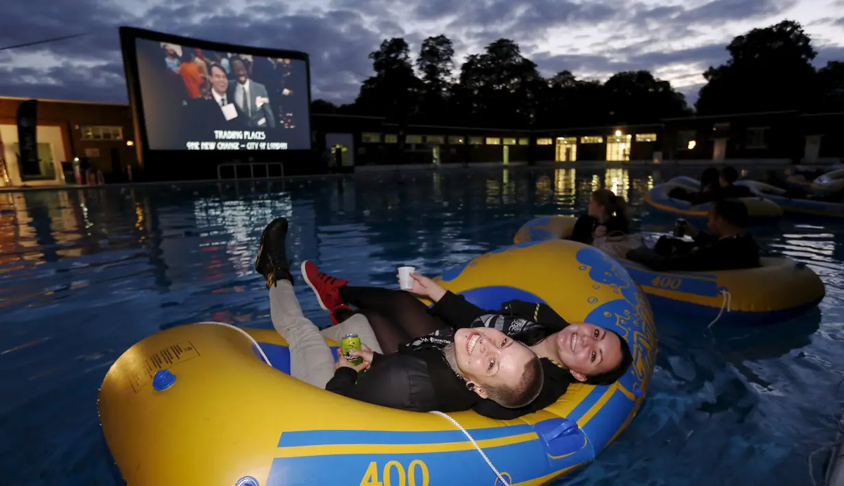 Penonton film tersenyum menunggu pemutaran film Steven Spielberg "Jaws" dengan ban karet di kolam renang di Brockwell Lido, London, Inggris, Kamis (17/9/2015). (REUTERS/Luke MacGregor)