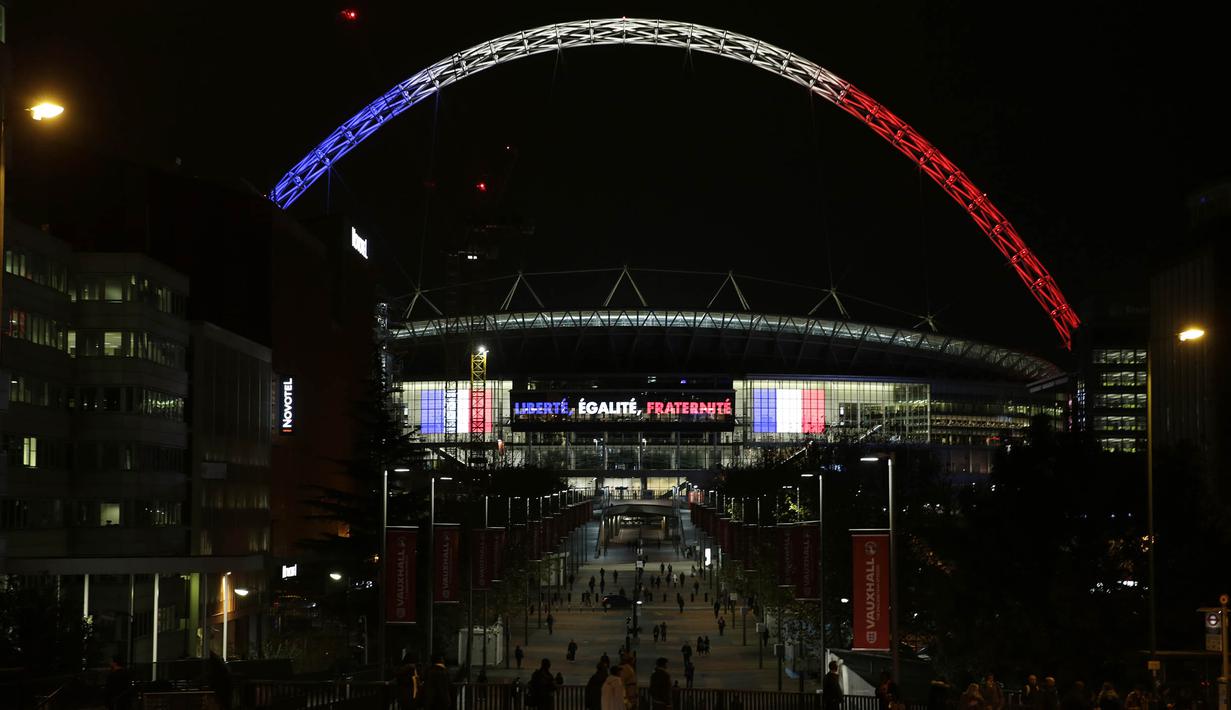 Sejumlah warga beraktifitas di sekitar Stadion Wembley yang dihiasi lampu berwarna bendera Prancis, Senin (16/11/2015). Lampu ini merupakan bentuk belasungkawa Inggris terhadap serangan terror di Paris. (Action Images via Reuters/Henry Browne)