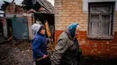 Seorang wanita berjalan di dekat rumah dengan jendela yang rusak setelah penembakan di Chasiv Yar, dekat Bakhmut pada 28 Februari 2023. Militer Ukraina mengatakan pada hari Selasa, Rusia menggempur permukiman di sekitar Bakhmut yang memiliki populasi sebelum perang sekitar 70.000 orang, namun kini menjadi reruntuhan. (Dimitar DILKOFF/AFP)