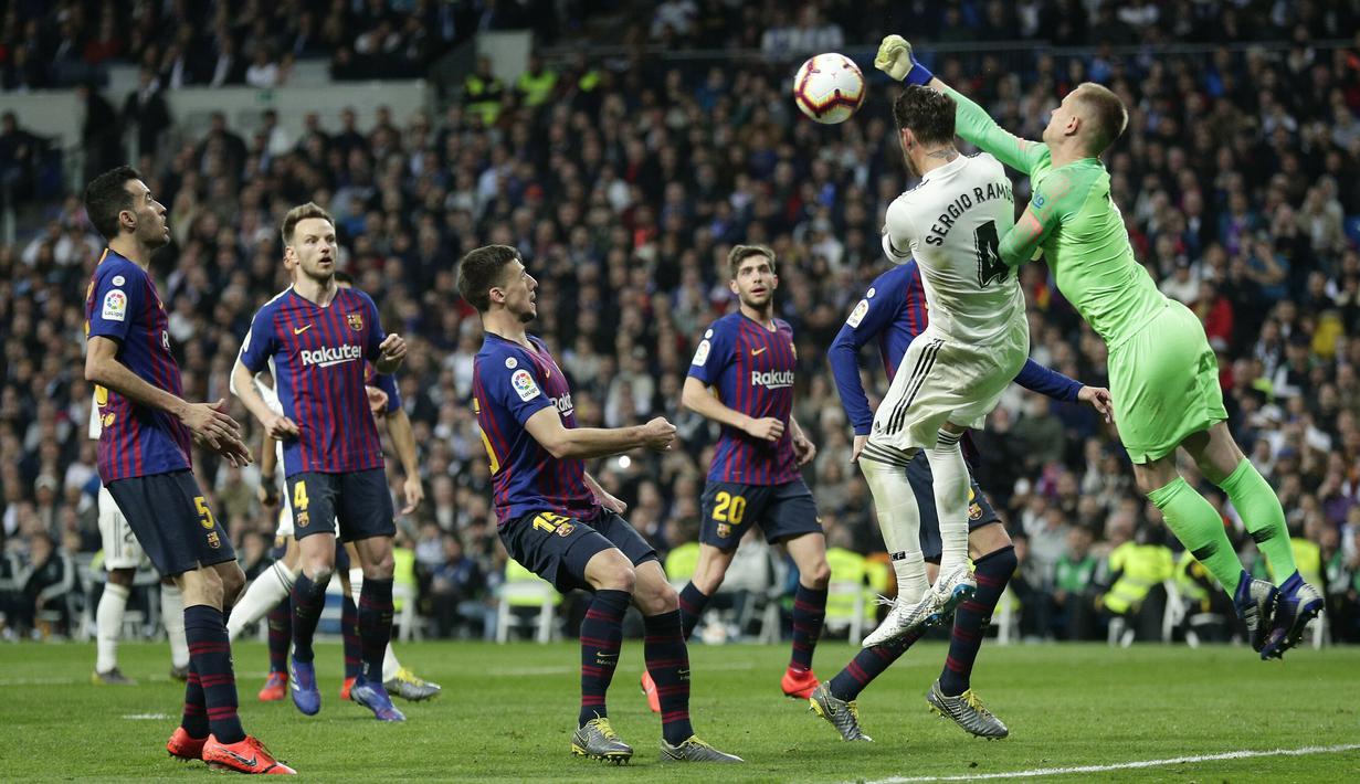 Kiper Barcelona, Marc-Andre ter Stegen, duel udara dengan bek Real Madrid, Sergio Ramos, pada laga La Liga di Stadion Santiago Bernabeu, Sabtu (2/3). Real Madrid takluk 0-1 dari Barcelona. (AP/Manu Fernandez)