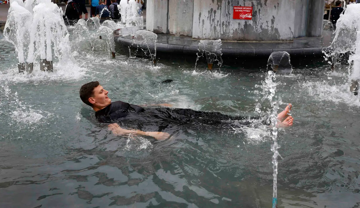Seorang suporter Inggris berendam di kolam air mancur yang berada di tengah Kota Lille, Prancis (16/6).Aksi ini mereka lakukan setelah mengatahui Timnas Inggris berhasil mengalahkan Wales dalam pertandingan piala Eropa 2016. (REUTERS / Wolfgang Rattay)
