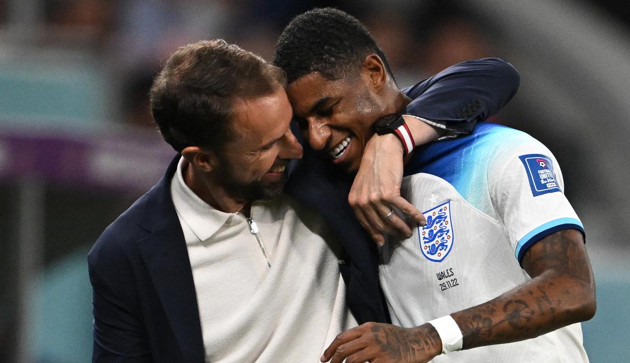 Striker Timnas Inggris, Marcus Rashford dipeluk pelatih Gareth Southgate usai ditraik keluar saat menghadapi Wales pada laga fase Grup B Piala Dunia 2022 Qatar di Ahmad Bin Ali Stadium, Doha (29/11/2022). Hingga kini Marcus Rashford total telah tampil dalam 51 laga bersama Timnas Inggris dengan torehan 15 gol dan 5 assist. Pada laga debutnya menghadapi Australia dalam sebuah laga persahabatan jelang Euro 2016 (27/5/2016), ia langsung mencetak satu gol dan membawa Inggris menang 2-1. (AFP/Paul Ellis)