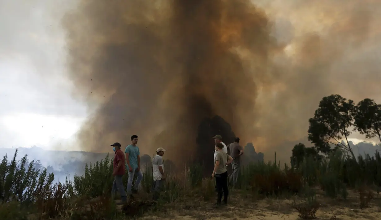 Penduduk setempat menyaksikan kebakaran hutan bergerak menaiki lereng menuju Desa Casal da Quinta, di luar Leiria, Portugal, 12 Juli 2022. Ratusan petugas pemadam kebakaran di Portugal terus memadamkan api di pusat negara yang memaksa evakuasi puluhan orang dari rumah mereka sebagian besar di desa-desa sekitar Santarem, Leiria, dan Pombal. (AP Photo/Joao Henriques)