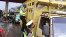 Polisi melakukan pemeriksaan dengan menaiki badan truk saat penyekatan larangan mudik lebaran di gerbang tol Cikupa, Kabupaten Tangerang, Banten, Kamis (6/5/2021). Penyekatan dilakukan seiring telah diberlakukan larangan mudik Lebaran mulai dari 6 hingga 17 Mei 2021.  (Liputan6.com/Angga Yuniar)