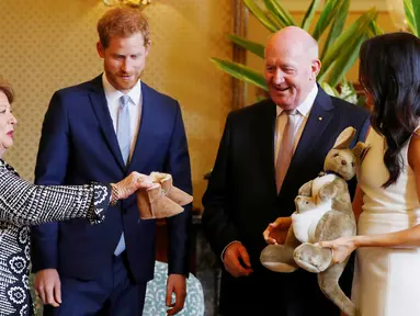 Pangeran Harry dan Meghan Markle bereaksi ketika menerima hadiah dari Gubernur Jenderal Australia Sir Peter Cosgrove dan istrinya, Lady Cosgrove di Sydney, Selasa (16/10). Meghan tampak senang menerima hadiah bayi pertamanya. (Phil Noble/Pool via AP)