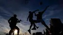 Orang-orang bermain bola basket saat matahari terbenam di sebuah lapangan di pusat Vilnius, Lithuania, Rabu, (15/7 2020). (AP Photo/Mindaugas Kulbis)
 