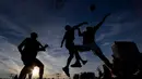 Orang-orang bermain bola basket saat matahari terbenam di sebuah lapangan di pusat Vilnius, Lithuania, Rabu, (15/7 2020). (AP Photo/Mindaugas Kulbis)
 