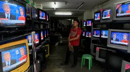 Seorang pekerja menyaksikan debat pertama kedua capres AS dari Partai Republik dan Partai Demokrat, Donald Trump dan Hillary Clinton dari layar televisi di sebuah toko elektronik di metro Manila, Filipina, Selasa (27/9). (REUTERS/Romeo Ranoco)