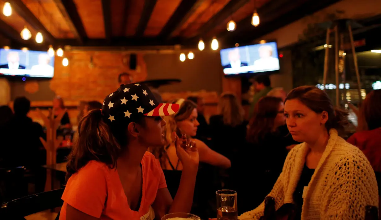 Dua wanita pendukung Partai Demokrat di Meksiko berbincang saat menyaksikan siaran televisi debat terakhir Capres AS Donald Trump dan Hillary Clinton di Sebuah Restoran di Meksiko, (19/10). (Reuters/Carlos Jasso)
