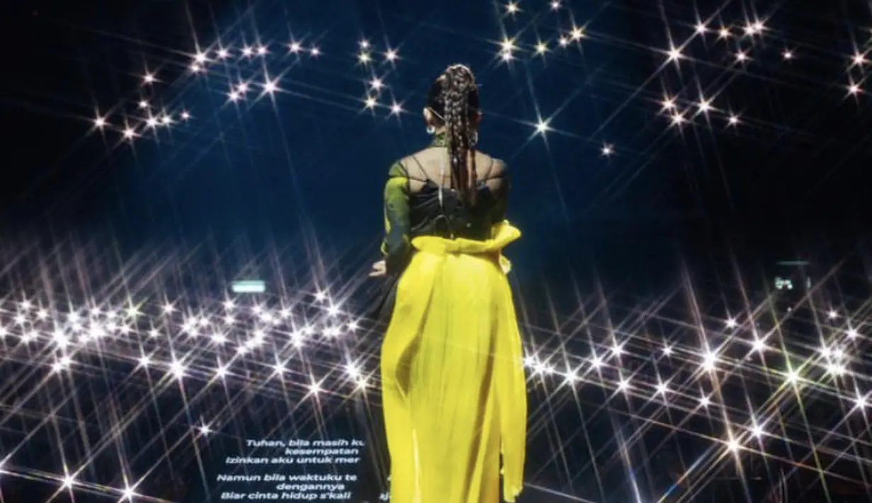 Meski tampak belakang, terlihat Rossa mengenakan rok kuning dengan spaghetti strap hitam sebagai atasan. Dengan gaya rambut kepang diikat ke belakang. (@itsrossa910)