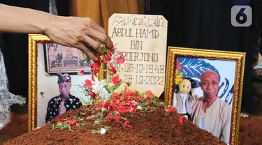 Foto almarhum Abdul Hamid alias Pak Ogah diletakan di atas makamnya di TPU (Tempat Pemakaman Umum) Jatisari, Bekasi, Jawa Barat, Kamis (29/12/2022). Pak Ogah salah satu pengisi suara dalam serial film Si Unyil meninggal pada (28/12/2022) di usia 74 tahun. (Liputan6.com/Herman Zakharia)