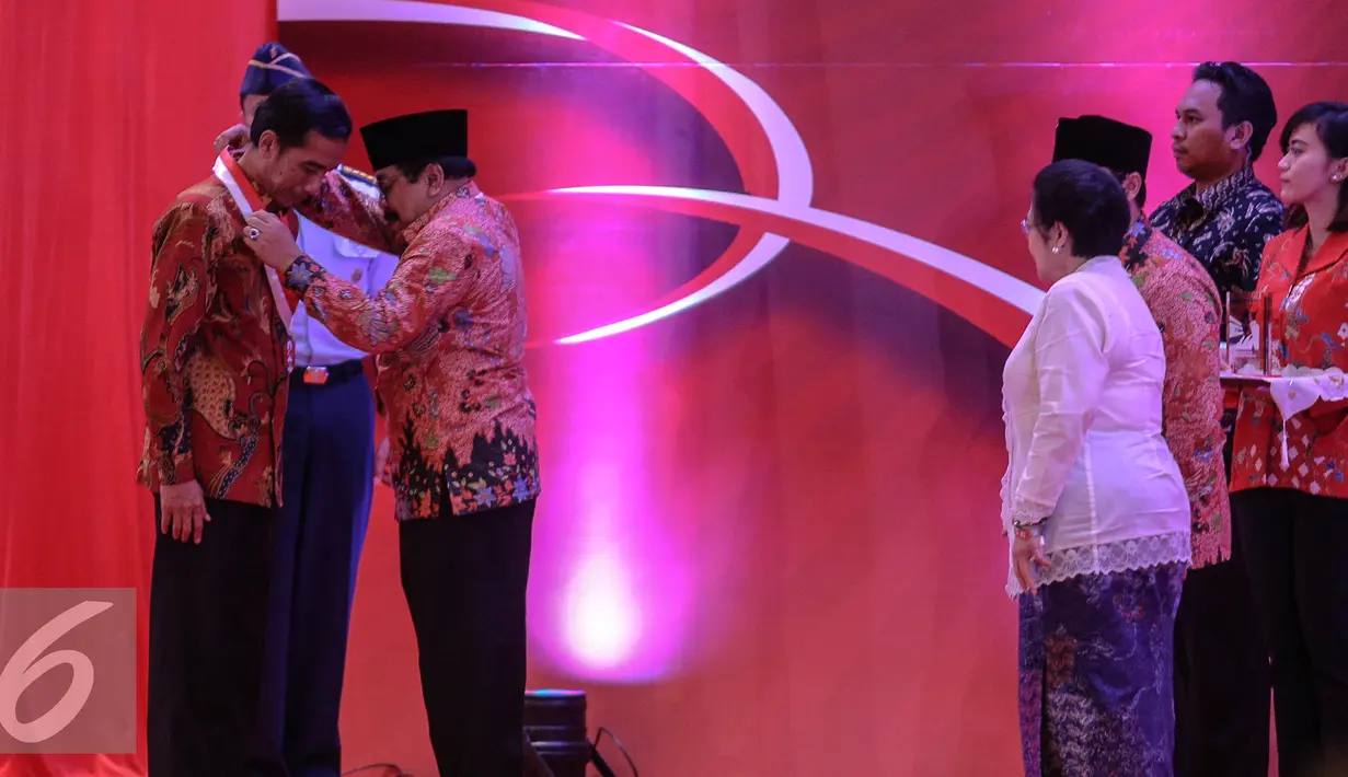 Gubernur Jatim sekaligus Ketum GMNI Soekarwo mengalungkan medali kepada Presiden Jokowi saat menghadiri pembukaan Kongres III Persatuan Alumni GMNI di Hall C-2, Ji-Expo, Kemayoran, Jakarta, Jumat (8/7/2015).  (Liputan6.com/Faizal Fanani)