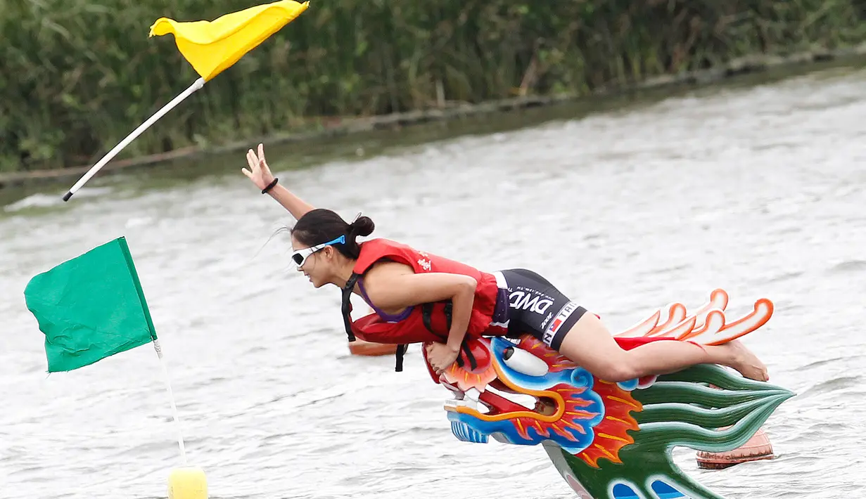 Seorang kapten berhasil meraih bendera usai mencapai garis finish perlombaan tradisional China, Dragon Boat di Taipei, Taiwan, Minggu (28/5). Perlombaan ini untuk mengenang kematian penyair Qu Yuan yang tenggelam pada 278 SM. (AP Photo/Chiang Ying-ying)