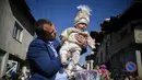 Seorang pria muslim Bulgaria menggendong putranya selama upacara sunat massal untuk anak laki-laki di Desa Ribnovo, 11 April 2021. Penduduk Desa Ribnovo adalah muslim berbahasa Bulgaria, kadang-kadang disebut sebagai "Pomaks" atau "orang yang menderita". (Nikolay DOYCHINOV/AFP)