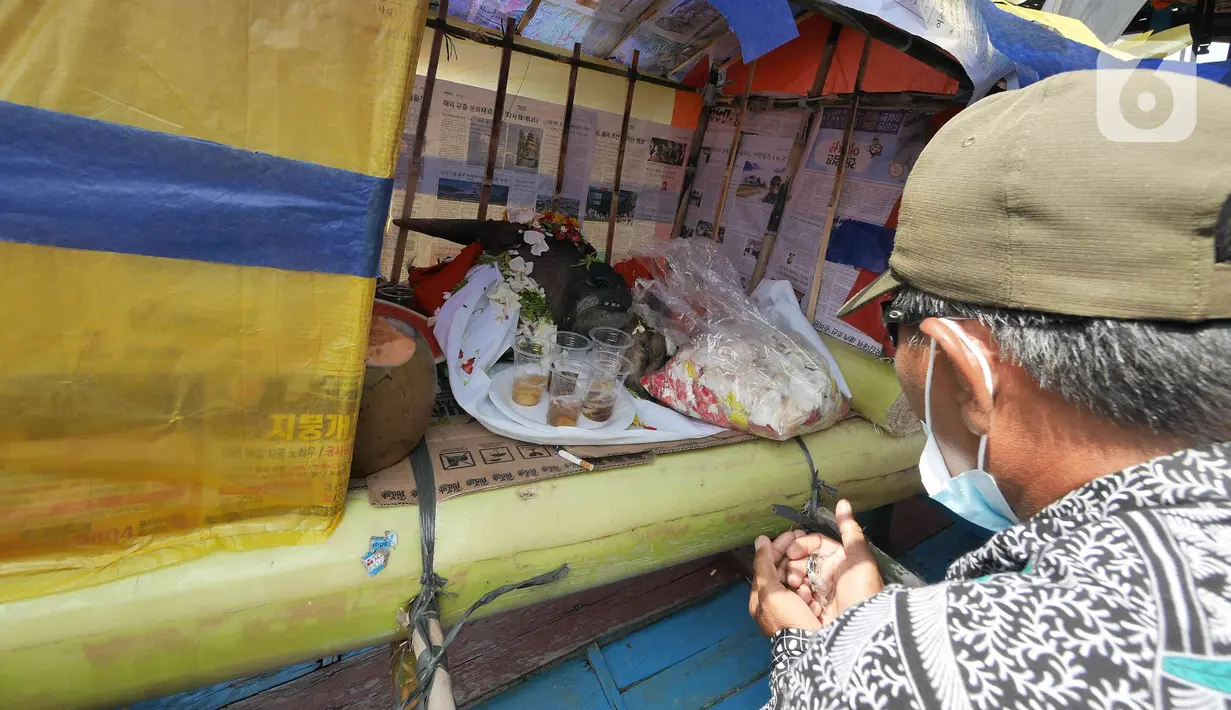 Sejumlah sesaji terlihat saat saat bersiap melarung replika kapal di Pantai Tarumajaya, Kabupaten Bekasi, Jawa Barat, Jumat (28/1/2022). Ritual sekaligus bentuk permohonan doa agar diberikan keselamatan dalam melaut. (Liputan6.com/Herman Zakharia)