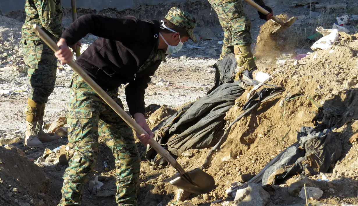 Polisi Irak menggali sebuah kuburan massal yang diduga berisi puluhan jenazah yang dieksekusi oleh kelompok ISIS di Kota Ramadi, sebelah barat Baghdad, Selasa (26/1). Kuburan massal tersebut berisi sisa-sisa sekitar 40 jasad. (AFP/ MOADH AL-DULAIMI)