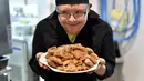 Asisten memasak down sindrom memegang sepiring kue Maroko pesanan pengunjung restoran "Le Reflet" di Nantes, Prancis Barat, 9 Februari 2017. Lelievre (26), mempekerjakan sejumlah karyawan yang memiliki down syndrome di restorannya. (LOIC VENANCE/AFP)