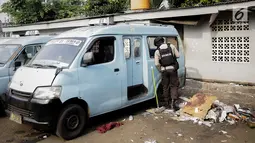 Anggota Brimob mengecek kondisi angkutan kota (angkot) yang mengalami kerusakan akibat ledakan bom di Kampung Melayu, Kamis (26/5). Angkot yang terparkir tepat di depan toilet, dekat TKP bom bunuh diri itu belum dievakuasi. (Liputan6.com/Faizal Fanani)