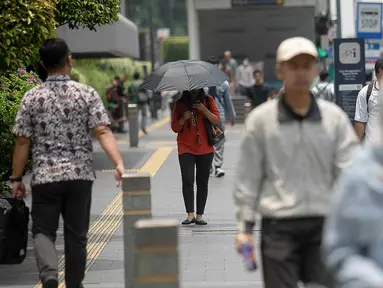 Warga beraktivitas pada siang hari sekitar pukul 11.54 WIB saat fenomena hari tanpa bayangan di kawasan Bundaran Hotel Indonesia (HI), Jakarta, Selasa (8/10/2024). (Liputan6.com/Herman Zakharia)