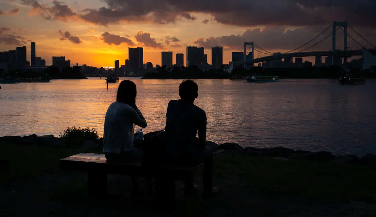 Pasangan menikmati matahari terbenam di Odaiba, Tokyo, (29/7). Nama "Odaiba" berasal dari sebutan untuk enam pulau di Teluk Tokyo yang dibangun sebagai benteng oleh Keshogunan Tokugawa. (AFP Photo/Martin Bureau)