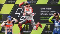 Pembalap Spanyol, Jorge Lorenzo (tengah) melompat merayakan selebrasi didampingi posisi kedua pembalap Marc Marquez dan posisi ketiga Valentino Rossi usai balapan MotoGP Catalunya di Sirkuit Catalunya, Montmelo, (17/6). (AFP PHOTO / Lluis Gen)