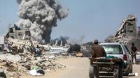 Orang-orang menyaksikan asap mengepul setelah serangan Israel di Jabalia, di Jalur Gaza utara pada 25 Mei 2025. (AFP/Bashar Taleb Basher)