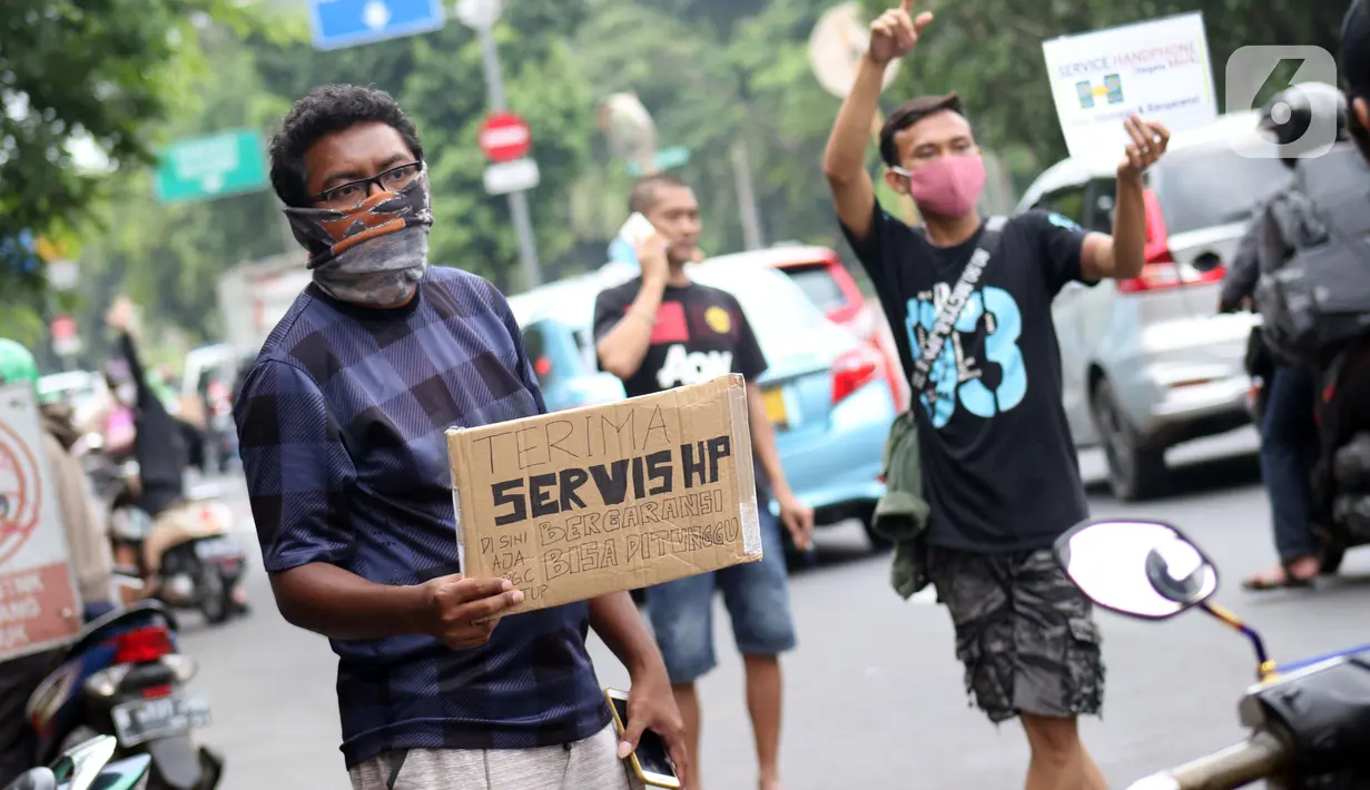 Penjual jasa perbaikan telepon genggam menawarkan jasanya di depan Mall Pusat Grosir Cililitan, Jakarta, Kamis (14/5/2020). Sejak pemberlakuan Pembatasan Sosial Berskala Besar yang berimbas pada penutupan pusat-pusat perbelanjaan, pendapatan mereka turun drastis. (Liputan6.com/Helmi Fithriansyah)