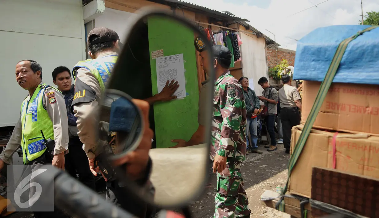 Petugas satpol PP menempel surat peringatan ke 3 di Kawasan Bukit Duri, Jakarta, Selasa (20/9). Pemkot Jaksel akan menertibkan bangunan dan permukiman di kawasan Bukit Duri yang berbatasan dengan Sungai Ciliwung. (Liputan6.com/Gempur M Surya)